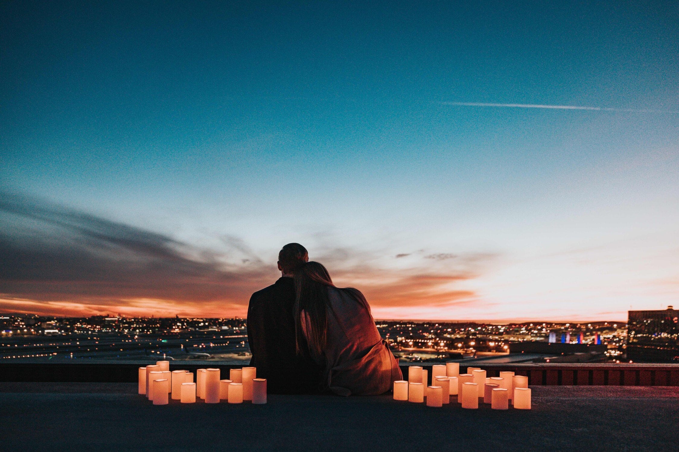 Couple sitting at dusk by candlelight looking over a town