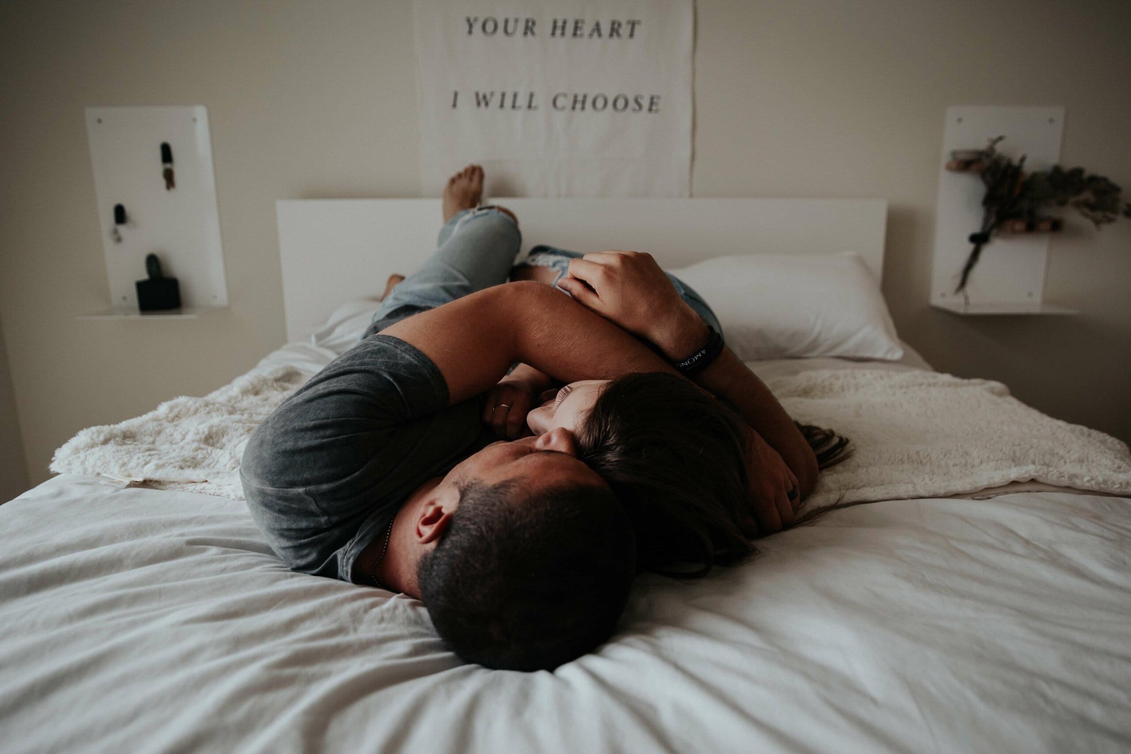 couple laying down and hugging on a bed