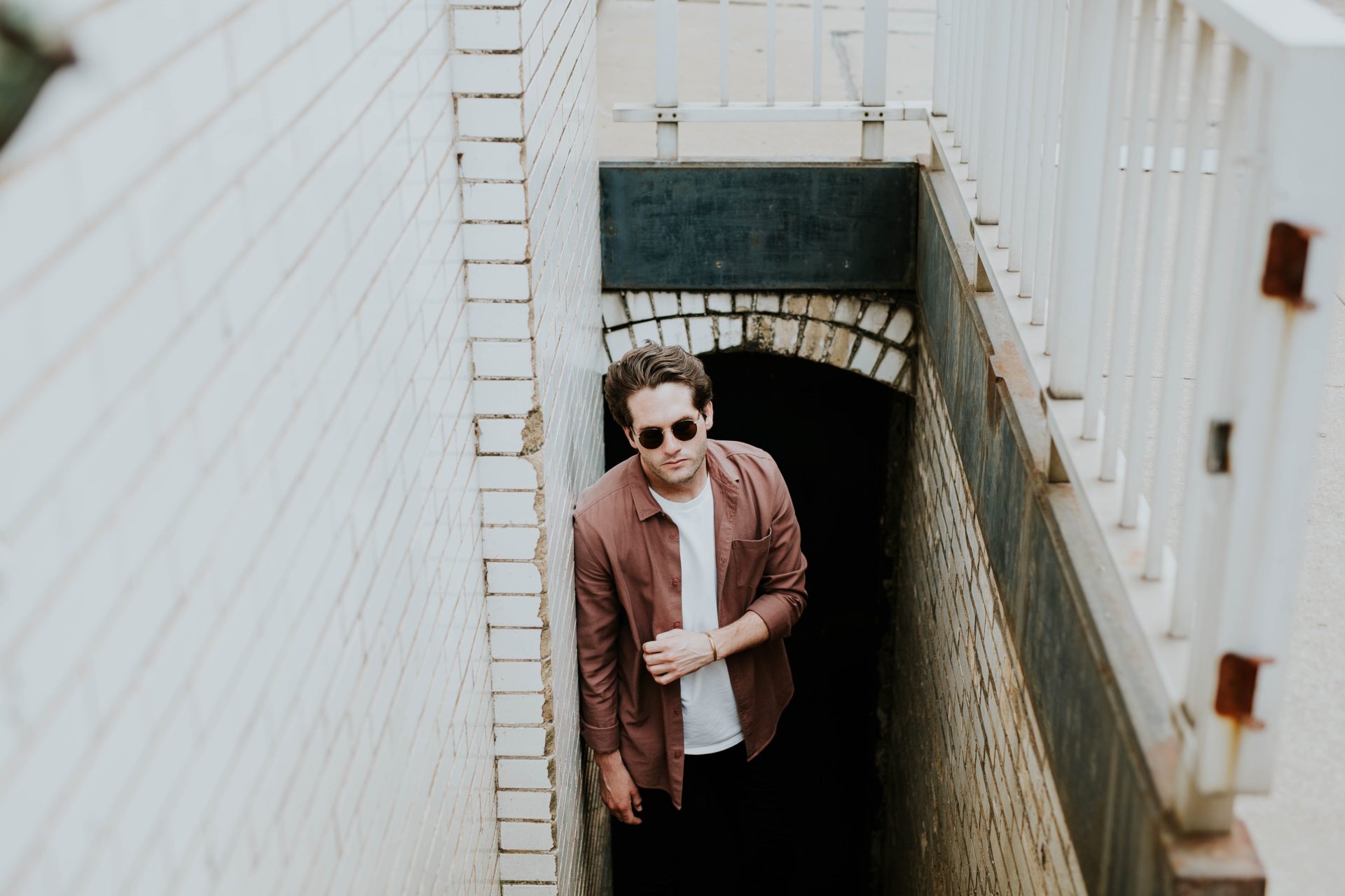 man in sunglasses looking up from the steps of an ally