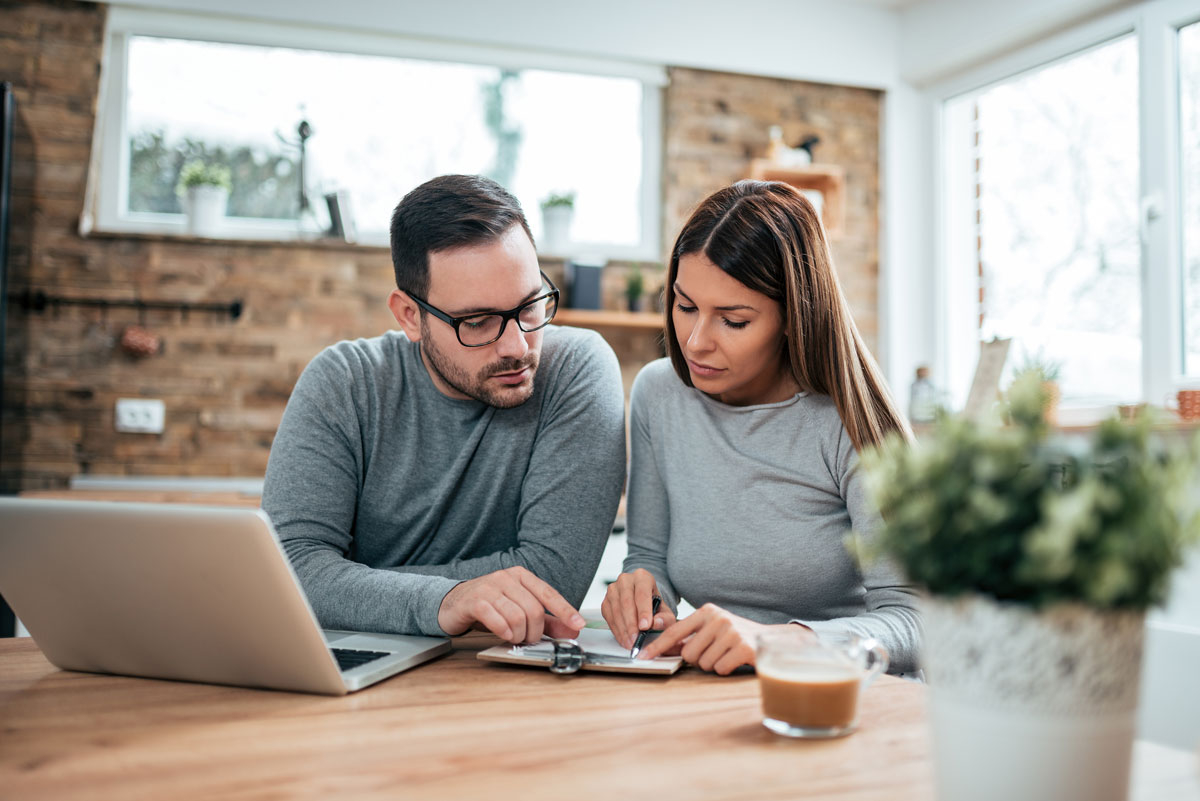couple sitting at desk together looking at clipboard