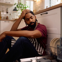 frustrated man sitting next to dishwasher