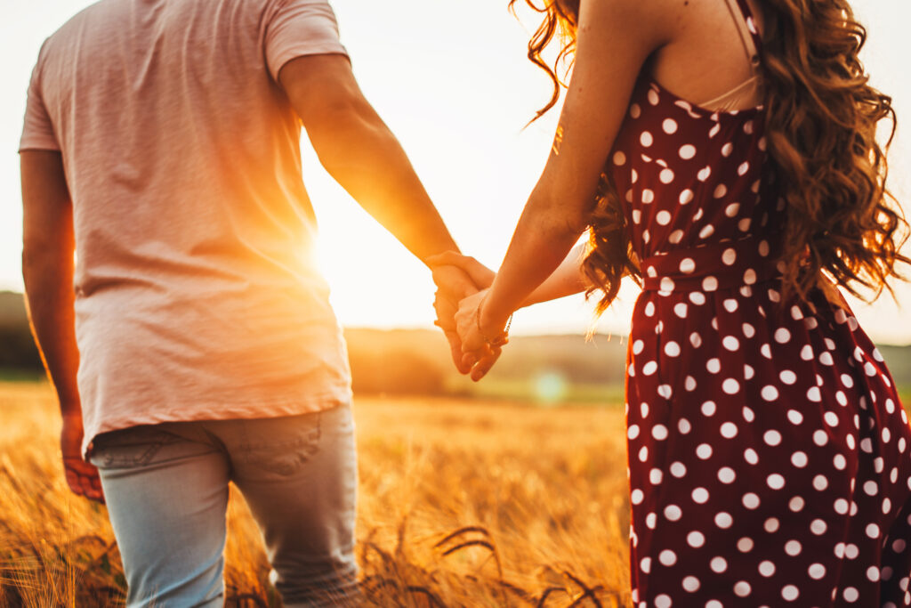 couple holding hands walking in a field