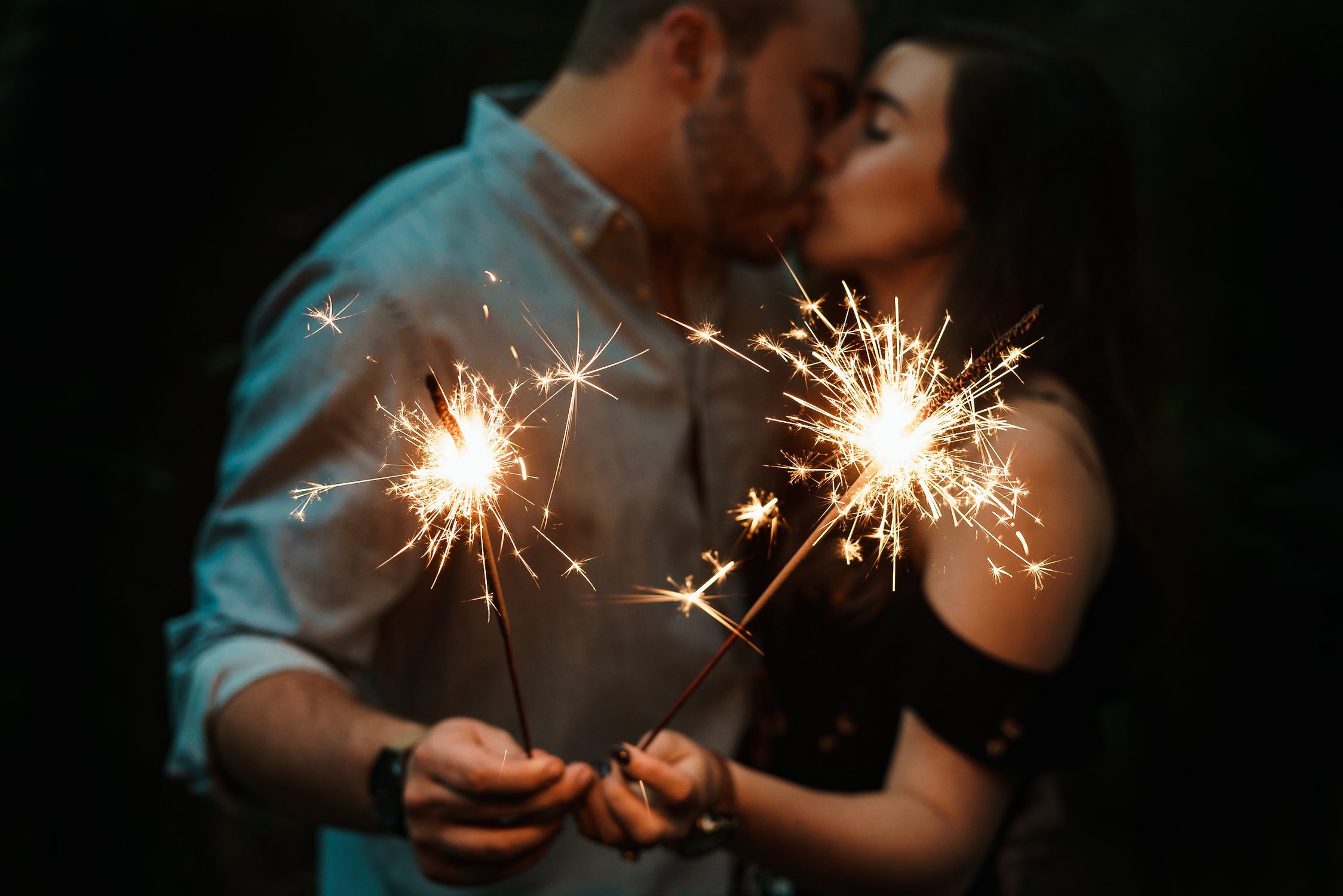 a couple kissing while holding sparklers