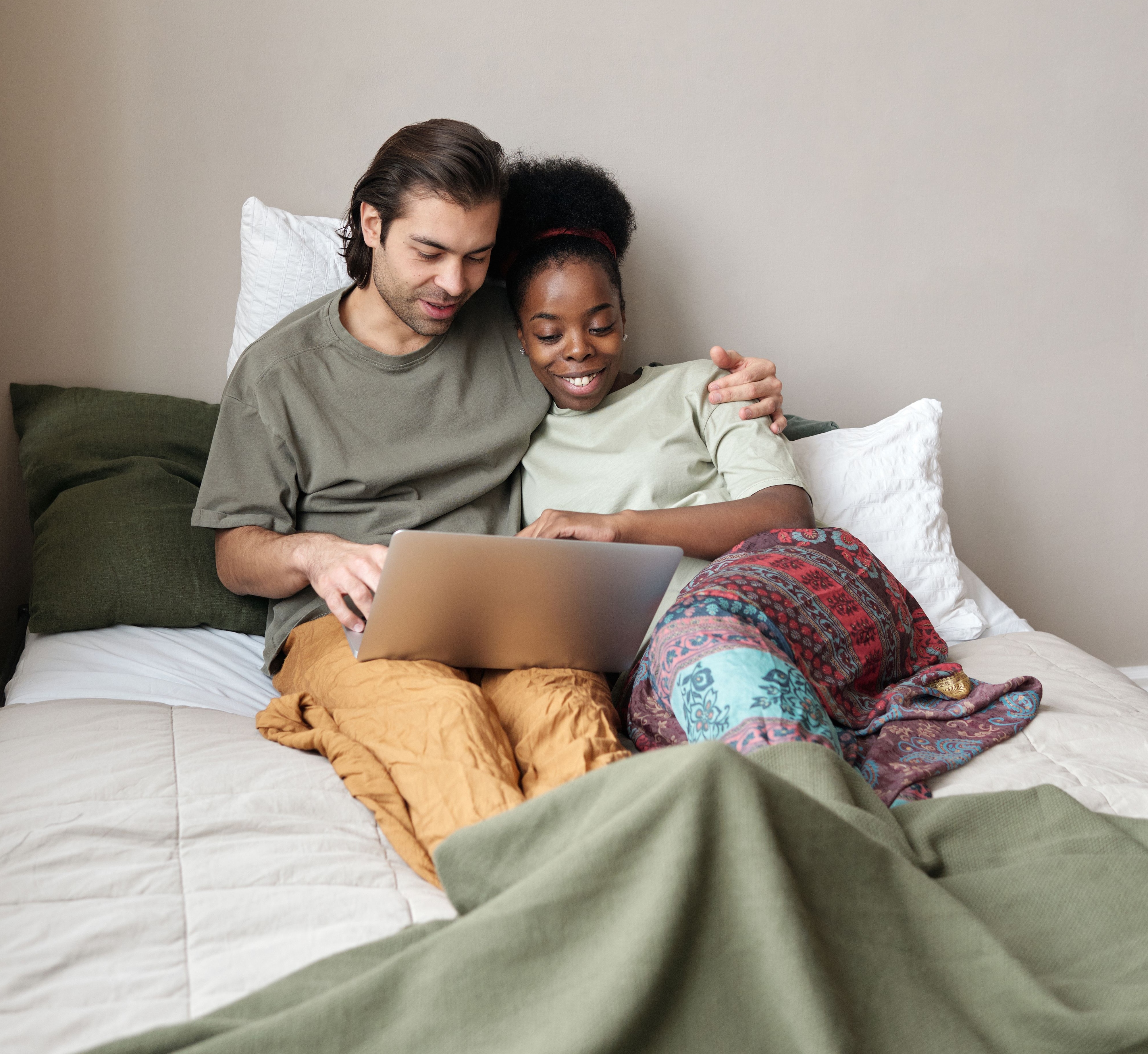Couple lying in bed watching videos on their computer