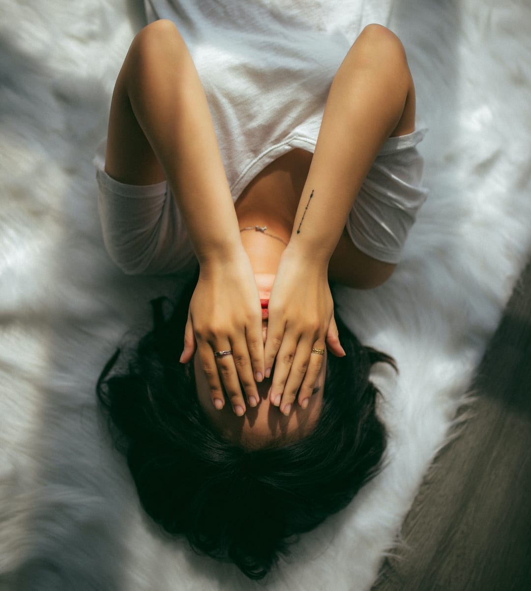 woman lying down with hands over her face