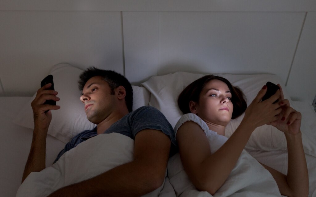 couple in bed on their phones